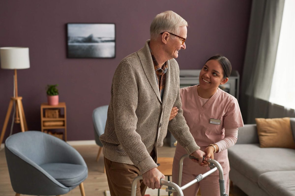 Discover the Safety, Security, and Peace of Mind Senior Living Can Provide Caregiver helping elder man with walker