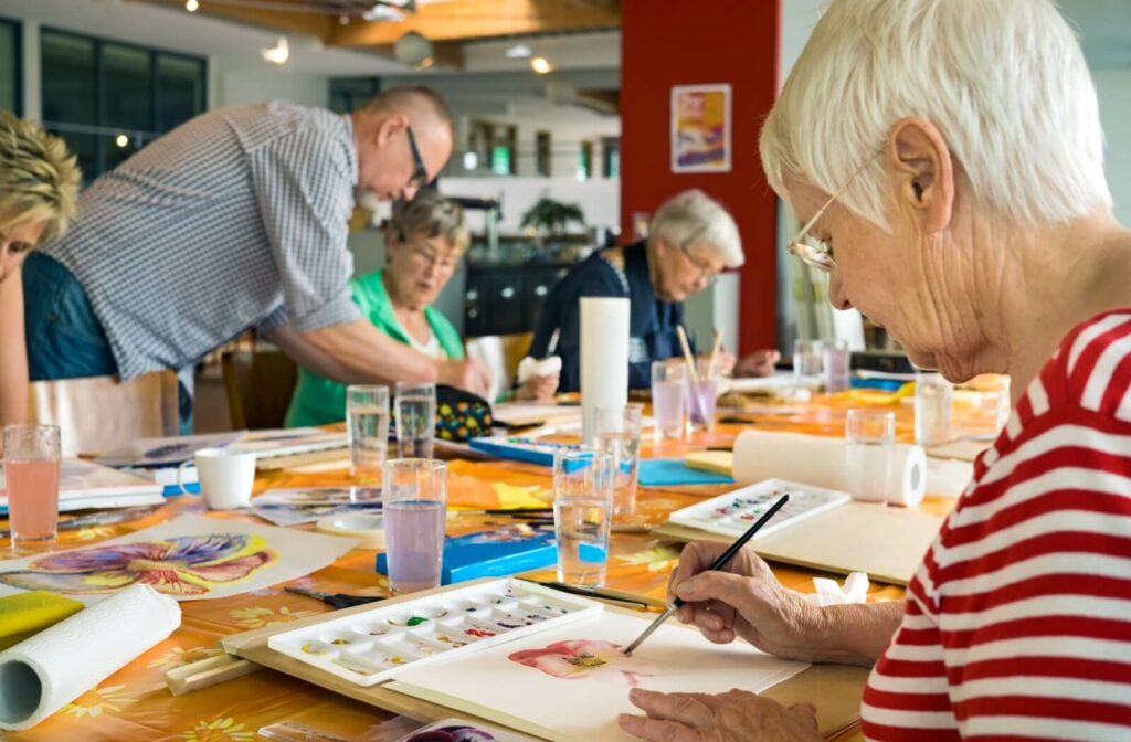 Seniors gathered around a communal table painting together.
