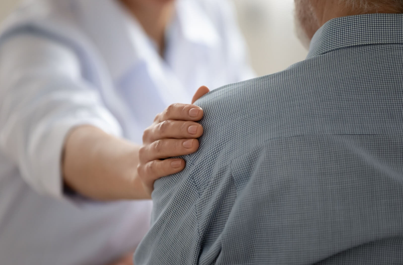 A kind caregiver reaching out to reassure an older adult with Alzheimer's disease.