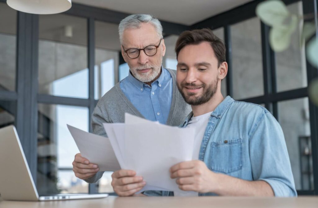 An adult helps their senior parent look through resources offered by their assisted living community to improve their life
