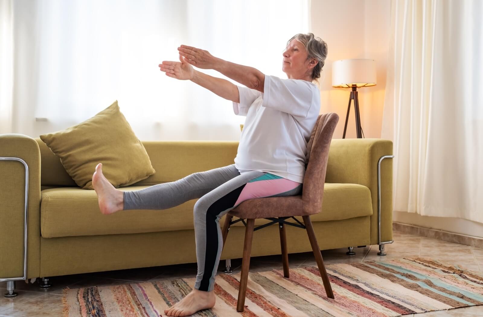 an elderly person doing chair therapy exercises.